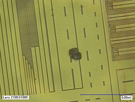 Cizorodá částice přimíchaná do čipu integrovaného obvodu (1000×)